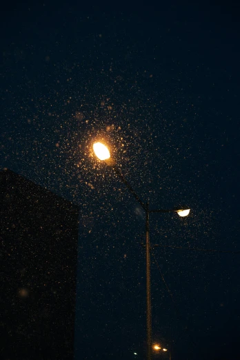 a street light that is next to a building, by Attila Meszlenyi, hailstorm, snowflakes falling, low quality photo, low iso