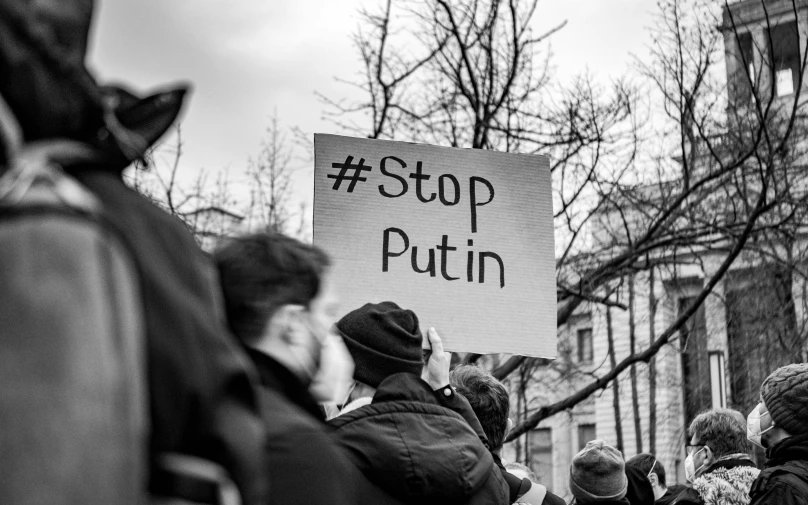 a group of people holding a sign that says stop putin, a black and white photo, by Julia Pishtar, pixabay, viennese actionism, winter, instagram post, brown, profile image