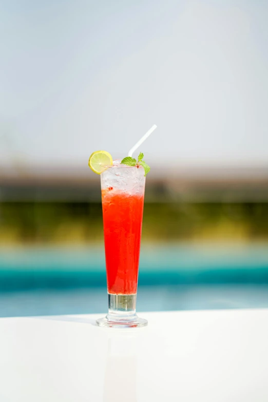 a drink sitting on top of a table next to a pool, bright red, profile image, resort, bright colour