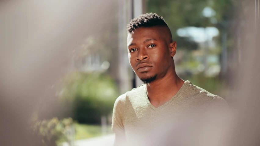 a young man standing in front of a window, inspired by Barthélemy Menn, pexels contest winner, hurufiyya, with brown skin, 2 1 savage, bright sunny day, thoughtful