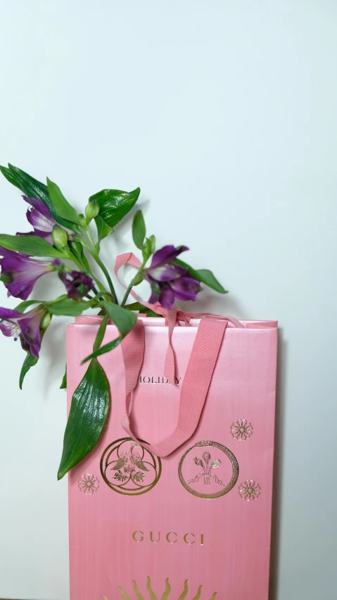 a pink gift bag with purple flowers in it, by Eden Box, lily flower, museum quality photo, gilded. floral, 4 k product photo