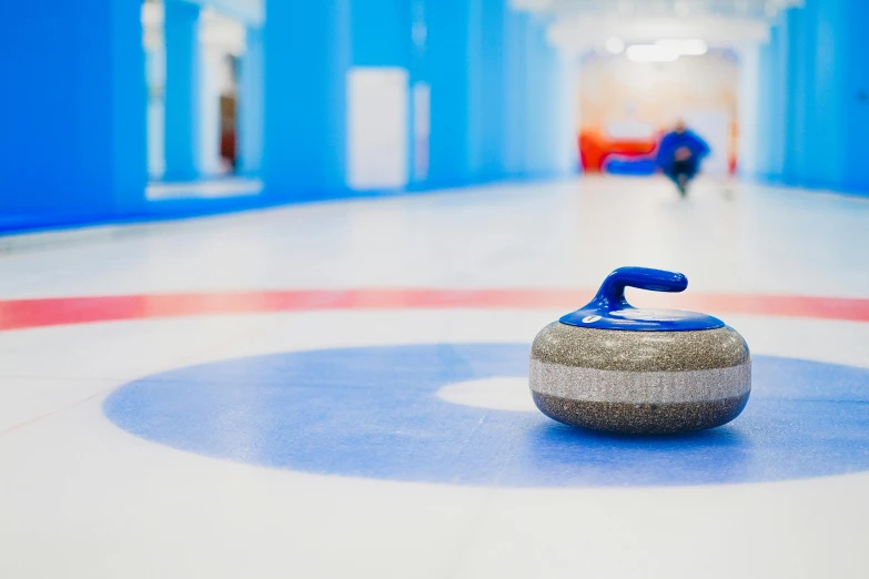a curling stone sitting on top of a curling rink, by Julia Pishtar, blue print, manuka, thumbnail, indoor shot