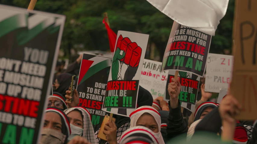 a large group of people holding up signs, by Julia Pishtar, hurufiyya, red and green, white hijab, [ cinematic, slide show