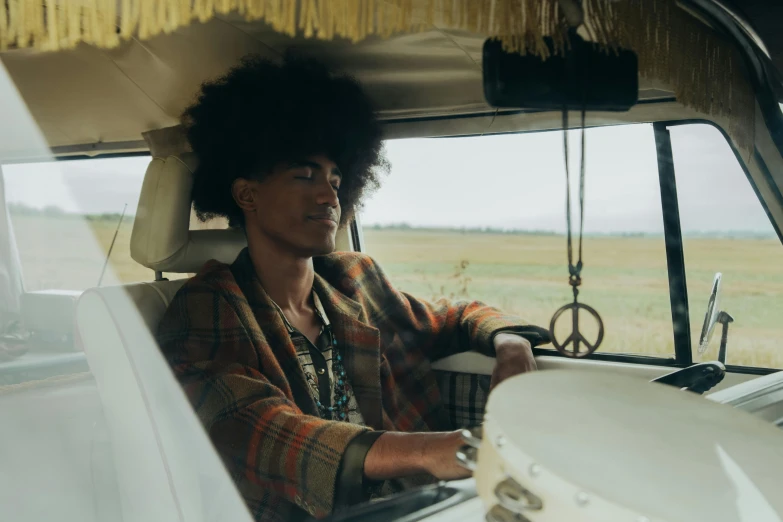 a woman sitting in the driver's seat of a van, trending on unsplash, afrofuturism, dressed in 1970s menswear, cottage hippie naturalist, black man with afro hair, robert sheehan