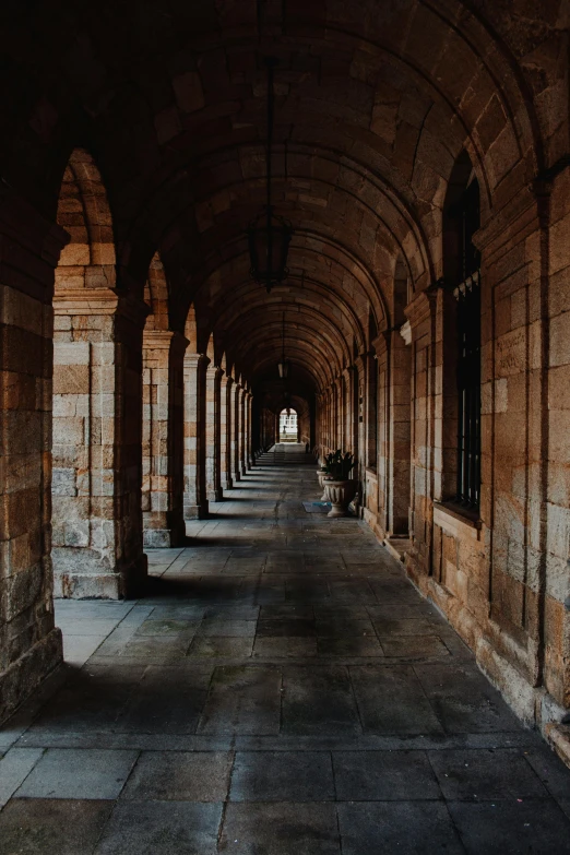 a long hallway in an old stone building, inspired by Sydney Prior Hall, pexels contest winner, romanesque, unsplash contest winning photo, in a row, college, streetscapes