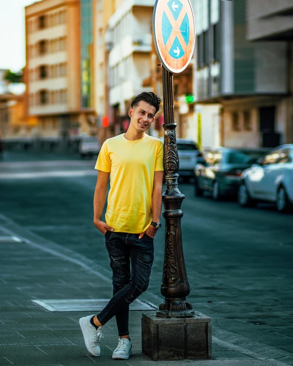 a man in a yellow shirt standing next to a street sign, by Julia Pishtar, pexels contest winner, cute young man, lgbt, jeans and t shirt, profile image