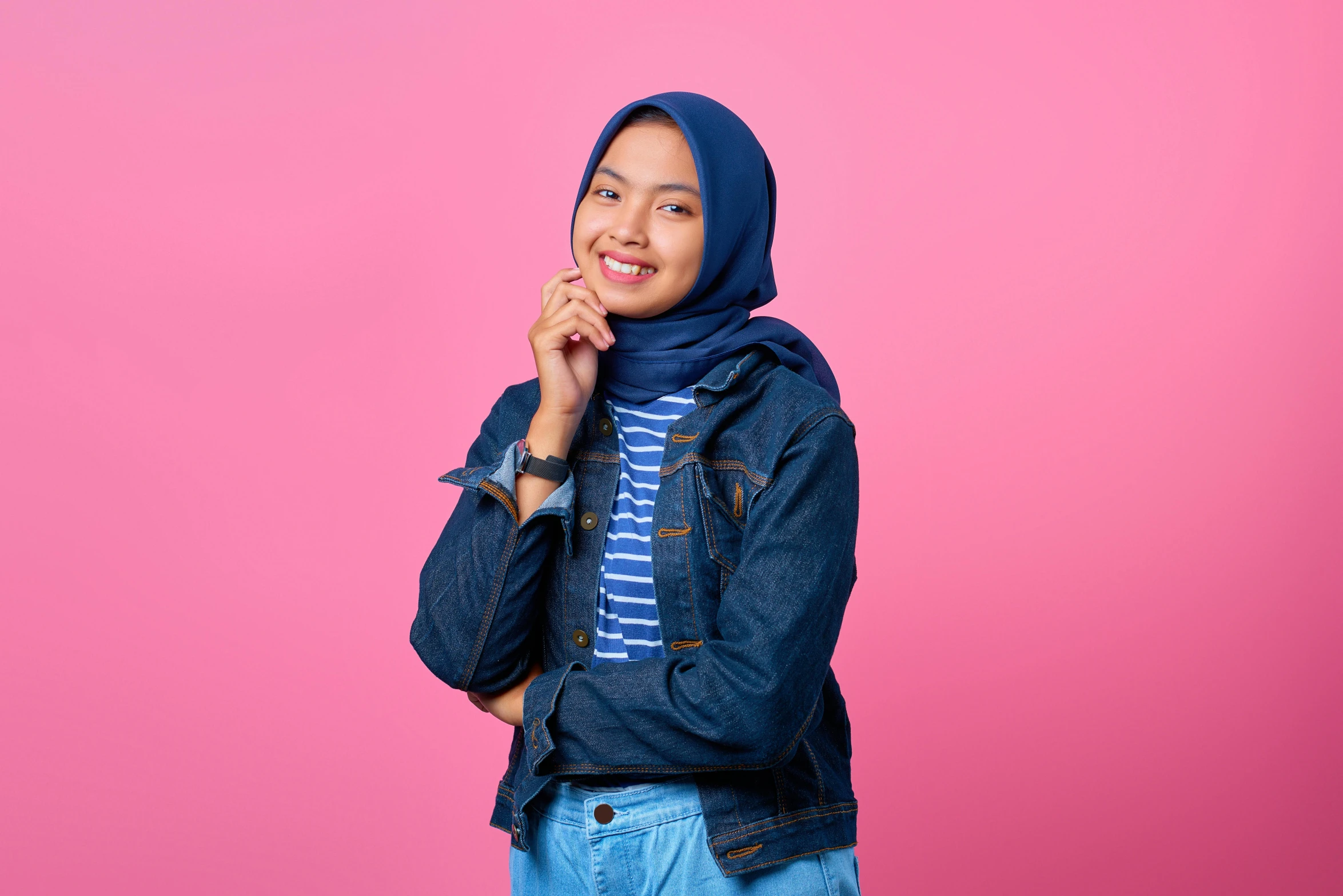 a woman wearing a hijab standing against a pink background, trending on pexels, hurufiyya, wearing double denim, 15081959 21121991 01012000 4k, smileing nright, q hayashida