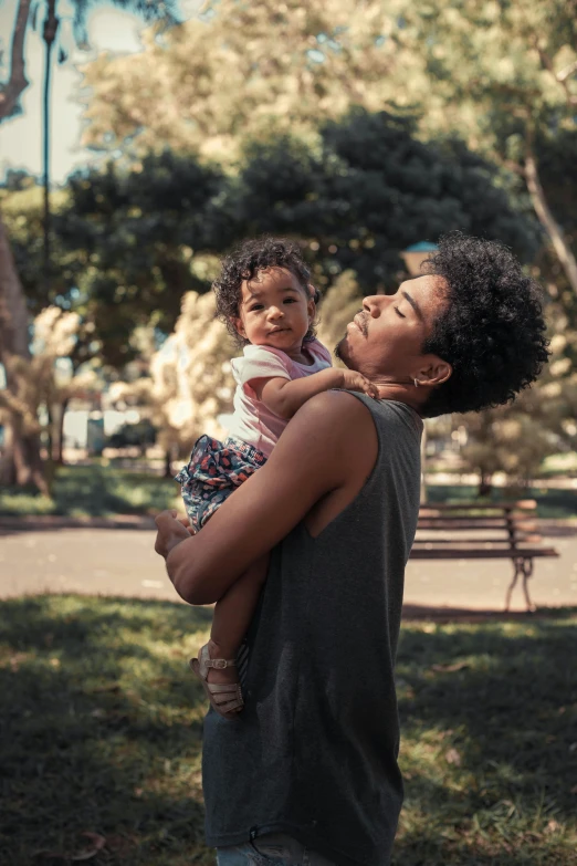 a man holding a small child in a park, dark skinned, lgbtq, multiple stories, 3 5 year brazilian mother