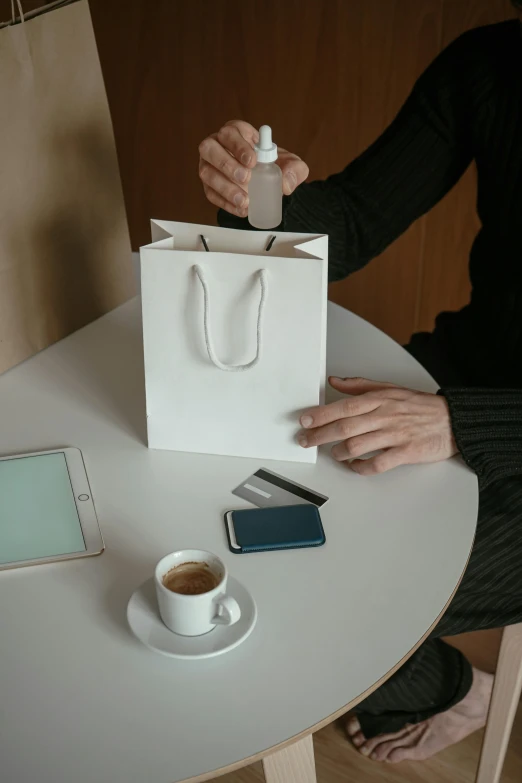 a person sitting at a table with a cup of coffee, fluid bag, carrying a bottle of perfume, product image, marketplace