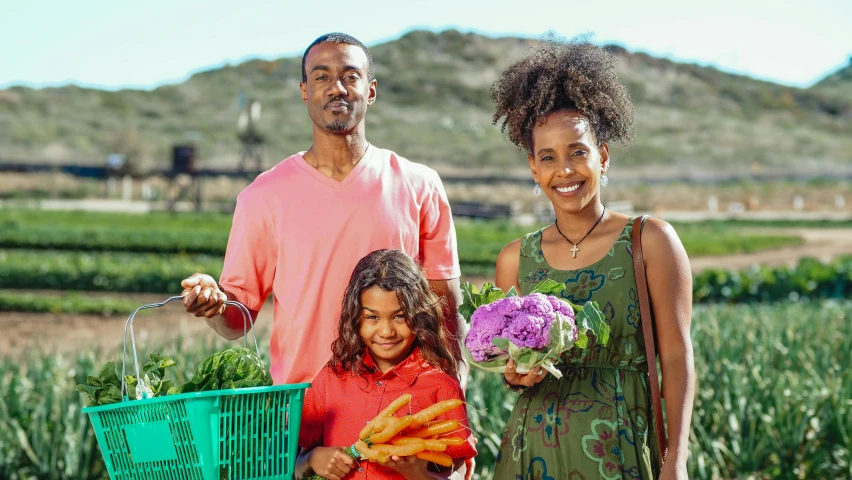 a man and woman standing next to a child holding a basket of vegetables, pexels contest winner, brown skinned, still image from tv series, oceanside, sustainable