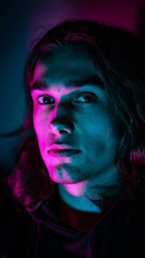 a man with long hair in a dark room, a character portrait, colorized neon lights, closeup headshot, instagram post, paul atreides