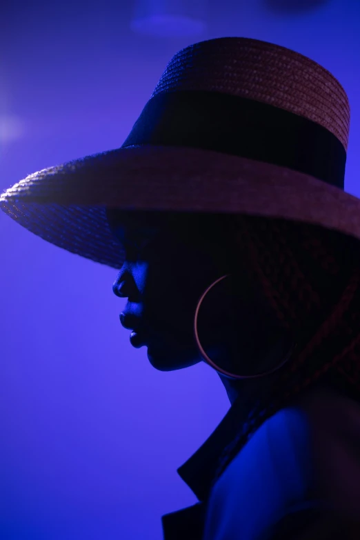 a close up of a person wearing a hat, by David Donaldson, pexels contest winner, afrofuturism, blue and purple lighting, woman silhouette, wearing straw hat, elegant profile posing