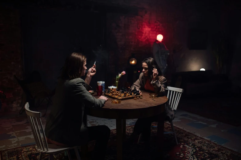 a group of people sitting around a wooden table, inspired by Elsa Bleda, pexels contest winner, serial art, dark cave room, medium shot of two characters, chess, promotional image