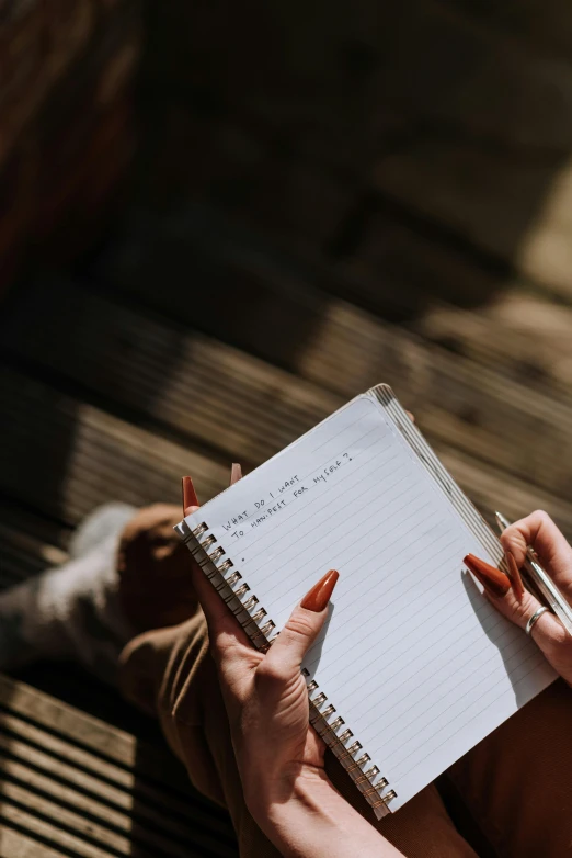 a woman sitting on a bench holding a notebook, pexels contest winner, scribbled lines, taking from above, instagram post, soft shade