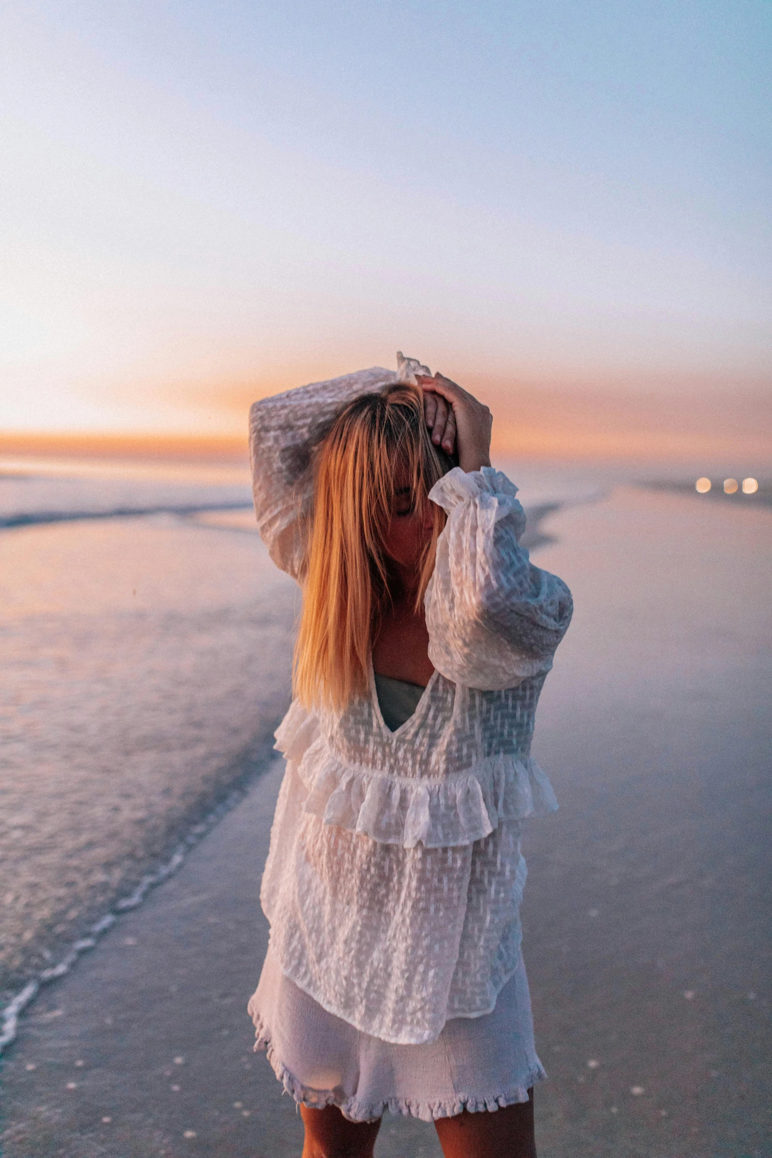 a woman standing on top of a beach next to the ocean, soft white glow, flowy hair, during dawn, the emerald coast