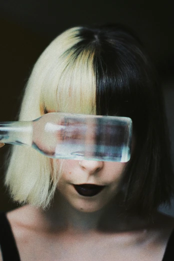 a woman holding a glass in front of her face, an album cover, unsplash, purism, black hair and white bangs, split dye, magnifying glass, a girl with blonde hair