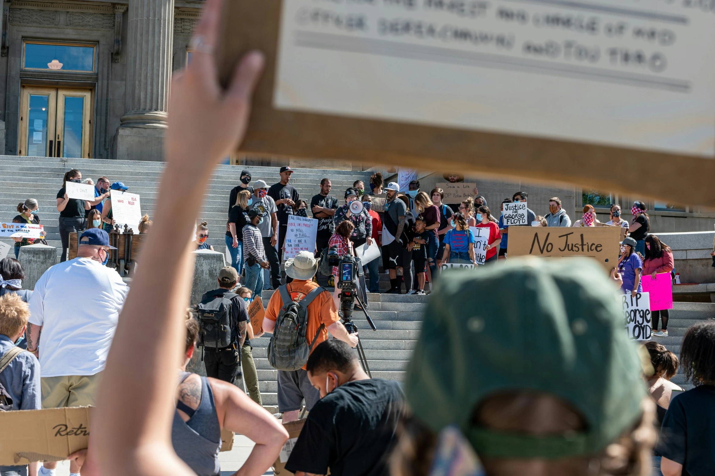 a group of people holding up signs in front of a building, by Dan Frazier, trending on reddit, capitol riot, with a figure in the background, montana, thumbnail