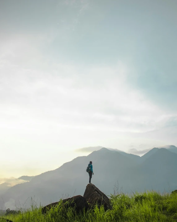 a person standing on top of a mountain, by Jessie Algie, trending on unsplash, sumatraism, multiple stories, conde nast traveler photo