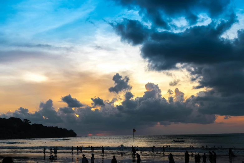 a group of people standing on top of a beach, pexels contest winner, sunset with cloudy skies, bali, thumbnail, festivals