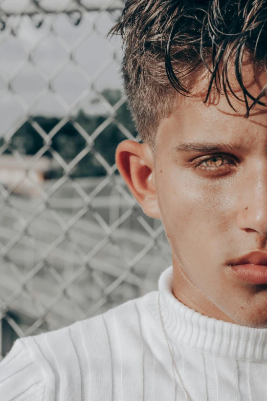 a young man standing in front of a chain link fence, an album cover, trending on pexels, grey colored eyes, non binary model, teen boy, wide eyed