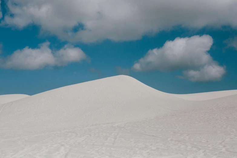 a man riding a snowboard down a snow covered slope, by Daniel Seghers, unsplash contest winner, minimalism, carribean white sand, big clouds, buried in sand, background image