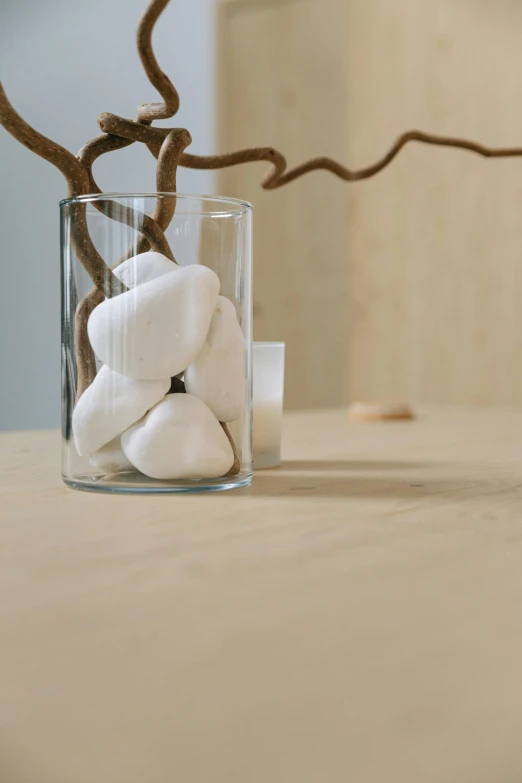 a vase filled with rocks sitting on top of a table, inspired by Isamu Noguchi, minimalism, branches, medium close shot, marshmallows, animation