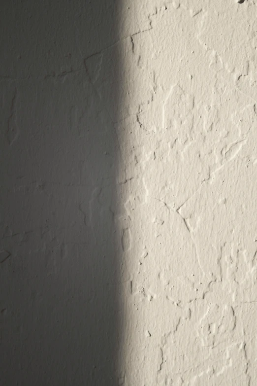 a clock mounted to the side of a white wall, inspired by Lucio Fontana, unsplash, light and space, detailed shadows and textures, sun glare, plaster, light stubble