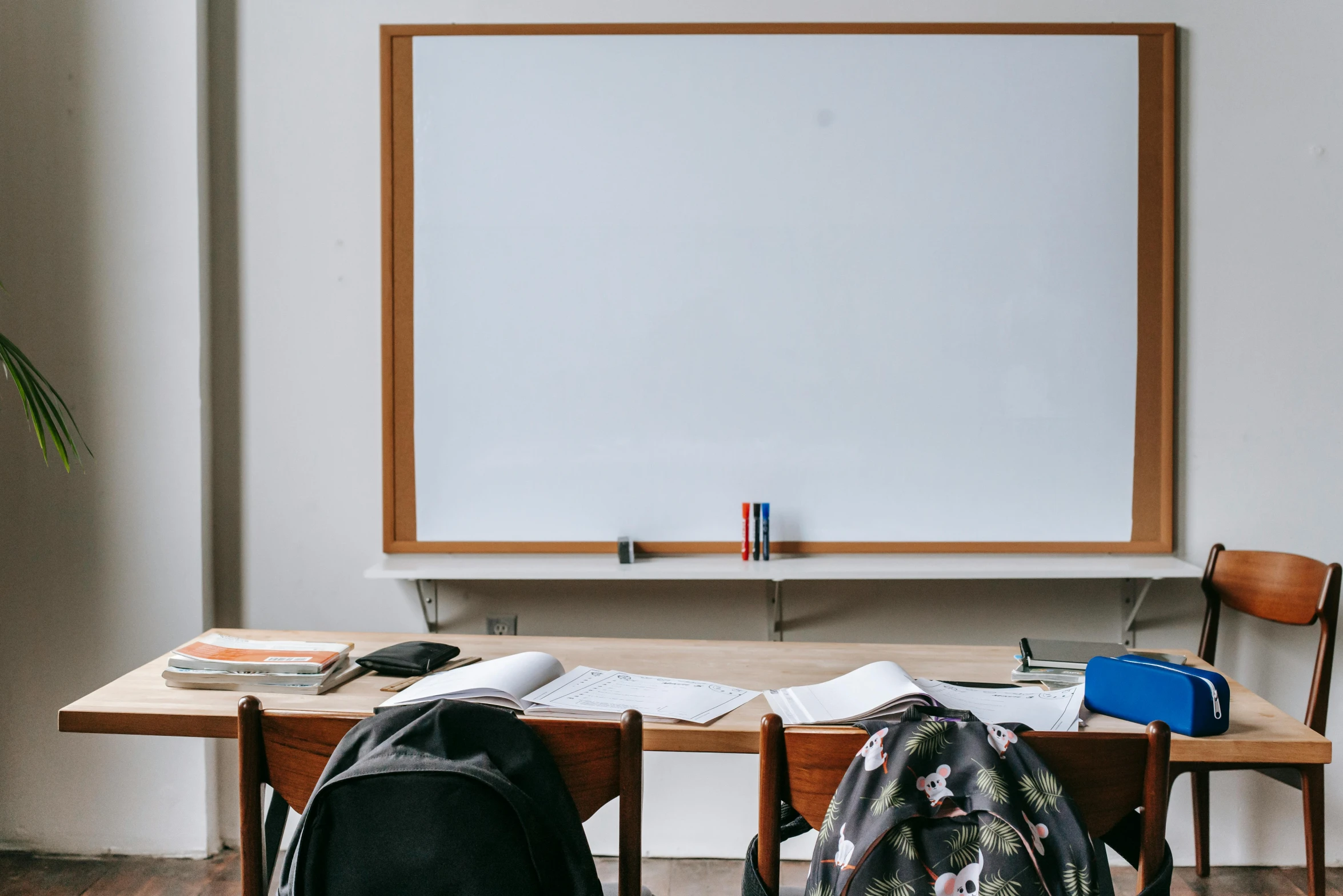 two backpacks sitting on a desk in front of a whiteboard, by Carey Morris, trending on unsplash, academic art, large screen, robed figures sat around a table, panoramic shot, florentine school