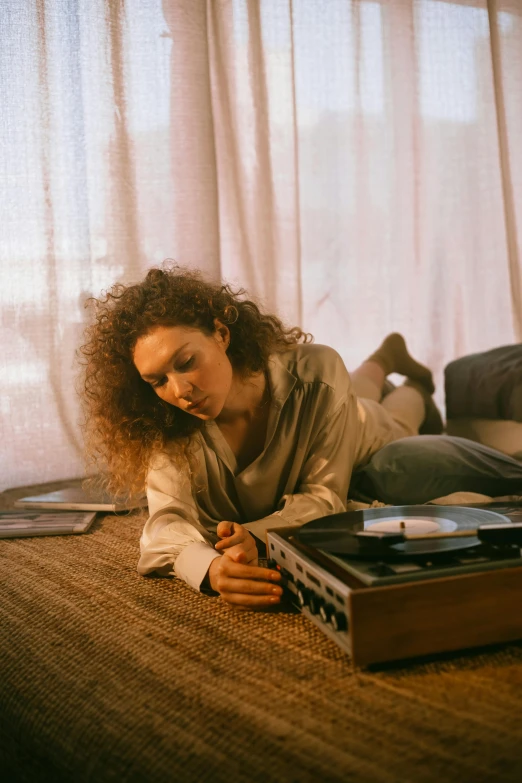 a woman laying on the floor next to a record player, inspired by Nan Goldin, trending on pexels, renaissance, brown curly hair, looking away, low sun, high quality photo