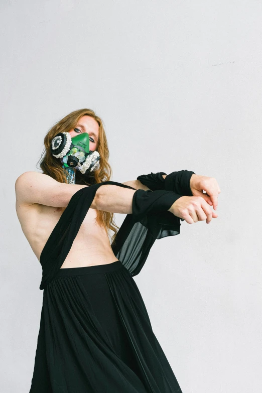 a woman in a black dress with a mask on, an album cover, unsplash, dirty green clothes, britt marling style 3/4, respirator, physical : tinyest midriff ever