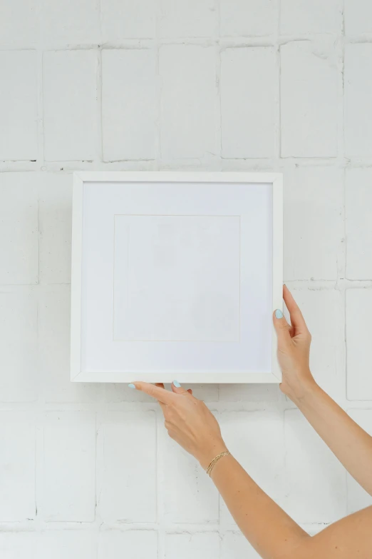 a woman hanging a picture frame on a wall, by Nicolette Macnamara, unsplash contest winner, visual art, all white render, 144x144 canvas, wide overhead shot, on a white table