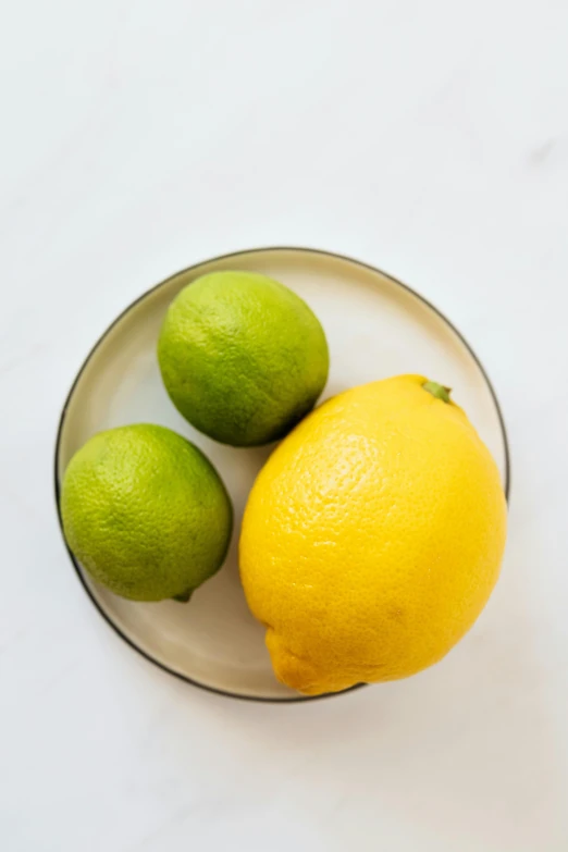 a bowl of lemons and limes on a table, product image, on a pale background, slight overcast, rule of three