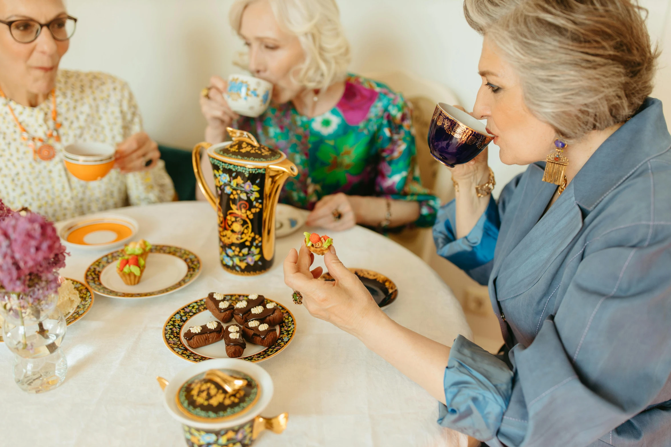 a group of older women sitting around a table, a still life, by Zofia Stryjenska, trending on pexels, cloisonnism, chocolate, seinfeld fancy tea party, blond, instagram photo