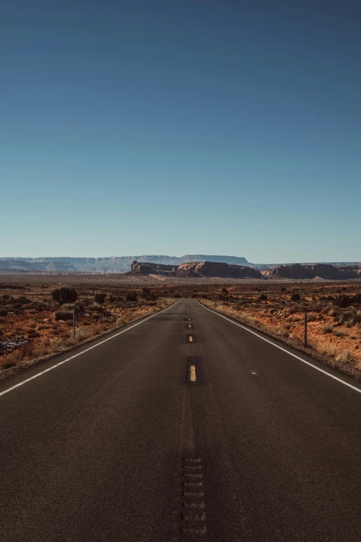 an empty road in the middle of the desert, unsplash, clear blue skies, moab, giant crater in distance, background image