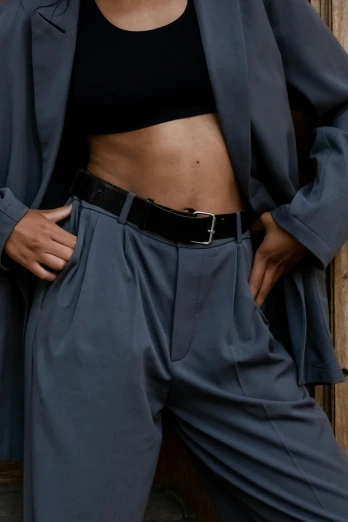 a woman in a black top and gray pants, trending on pexels, adonis belt, desaturated color, dressed in expensive clothes, zoomed in