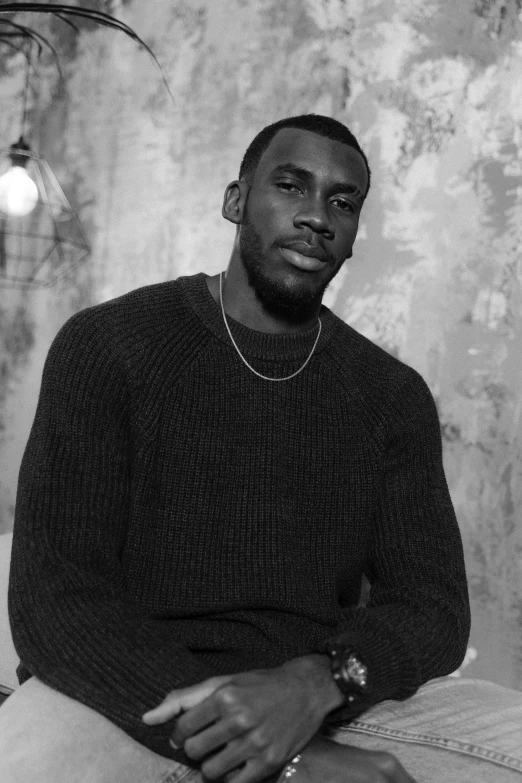 a black and white photo of a man sitting on a bed, an album cover, inspired by Terrell James, trending on pexels, realism, wearing turtleneck, lebron james, handsome man, baptiste from overwatch