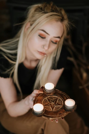 a woman holding a tray with candles in it, an album cover, trending on pexels, pentacle, headshot profile picture, female mage, holding a wood piece