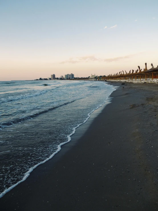 a beach filled with lots of umbrellas next to the ocean, in the evening, marbella, profile image