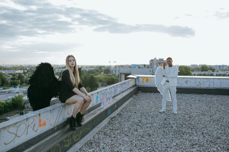 a man standing next to a woman on top of a roof, an album cover, by Emma Andijewska, pexels contest winner, wearing white suit, two models in the frame, performing a music video, photoshooting