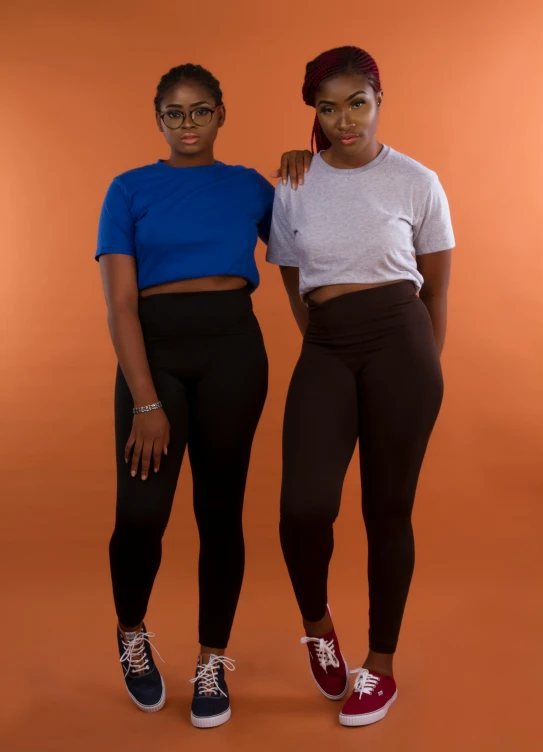 a couple of women standing next to each other, black leggings, ( ( dark skin ) ), promotional photography, 15081959 21121991 01012000 4k