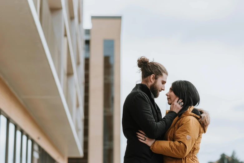 a man and a woman standing next to each other, by Jaakko Mattila, pexels contest winner, urban in background, bearded and built, holding each other, college