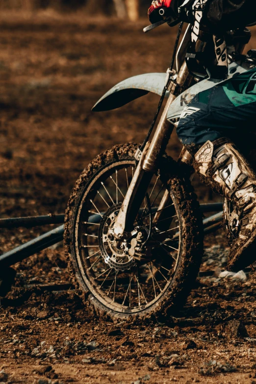 a man riding on the back of a dirt bike, pexels contest winner, photorealism, muddy colors, gold, close up details, wheels