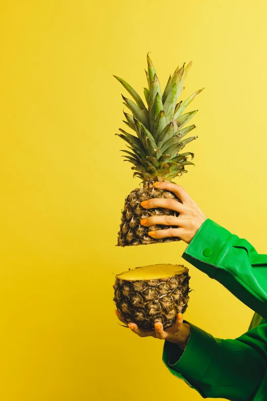 a woman holding a pineapple in one hand and a pineapple in the other, an album cover, by Julia Pishtar, trending on unsplash, magic realism, his palms are sweaty, colors: yellow, studio photo, made of glazed