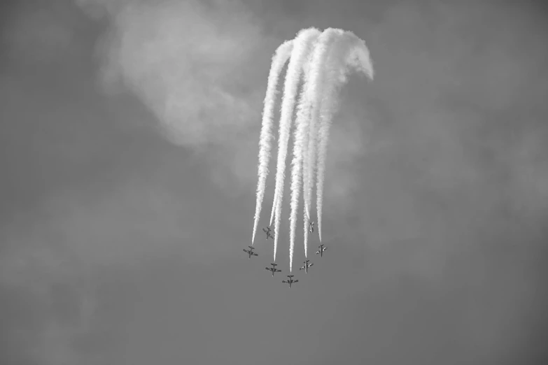 a group of jets flying through a cloudy sky, a black and white photo, by Jan Rustem, pexels contest winner, precisionism, reds, trail of smoke, low angle!!!!, silver wings
