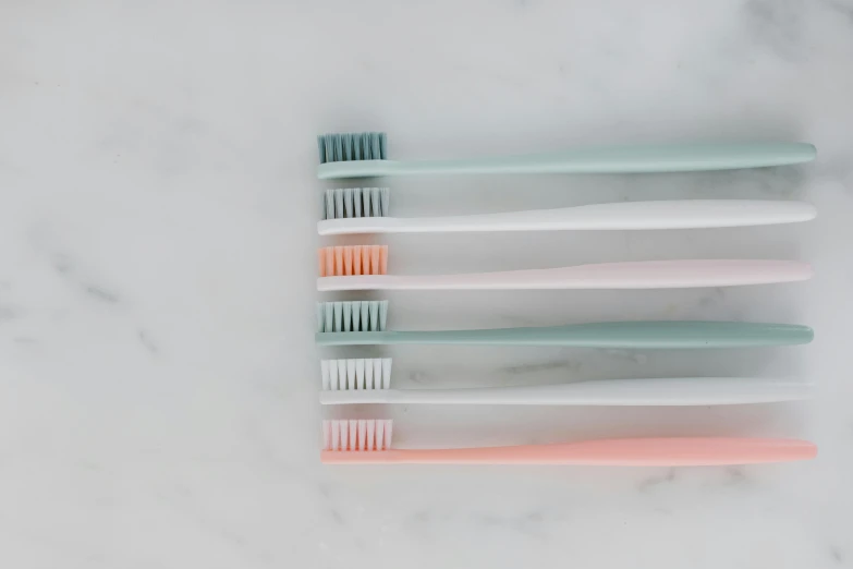 a group of toothbrushes sitting on top of a marble counter, muted pastels, 6 colors, calatrava, soft shapes