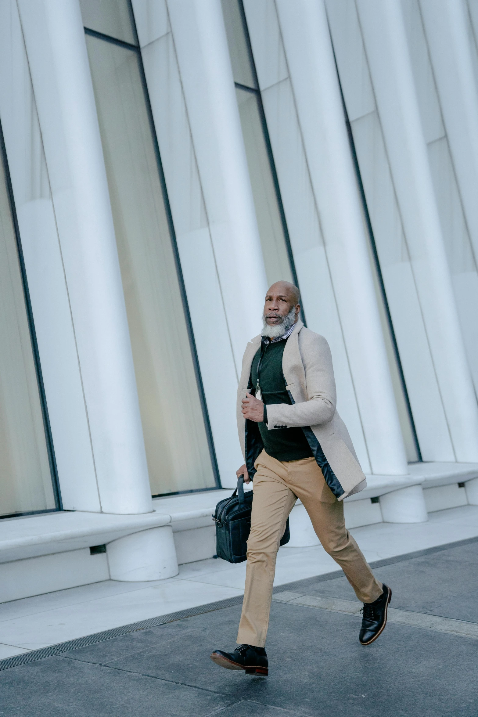 a man walking down a sidewalk in front of a building, inspired by Oluf Høst, happening, fashion shoot 8k, bald man, washington dc, at a mall