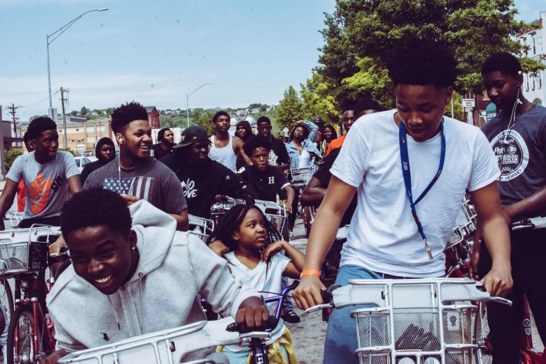 a group of people riding bikes down a street, by Washington Allston, pexels contest winner, black arts movement, rapper, teddy fresh, profile pic, paisley