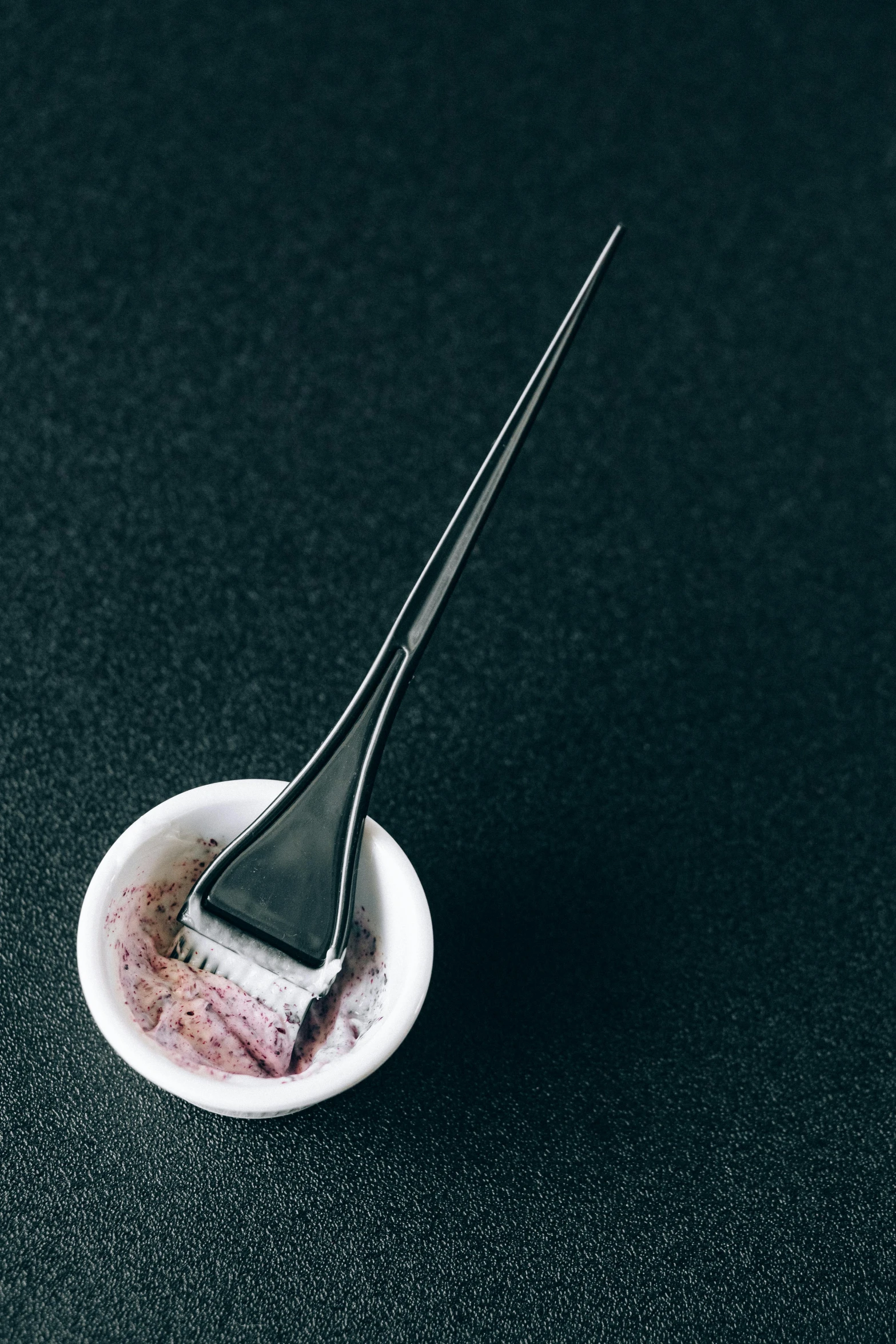 a small bowl of food with a fork in it, a photorealistic painting, inspired by Ryōhei Koiso, unsplash, purism, hair gel combed backwards, palette is black violet gray red, shaved, mold