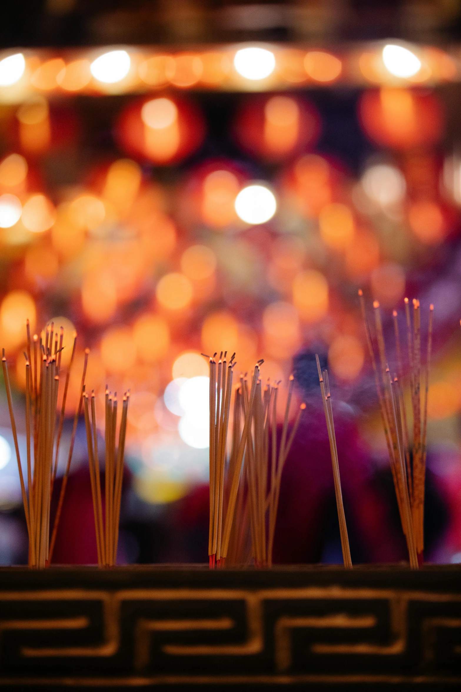 a row of incense sticks sitting on top of a table, waves of lights, set on singaporean aesthetic, shrine