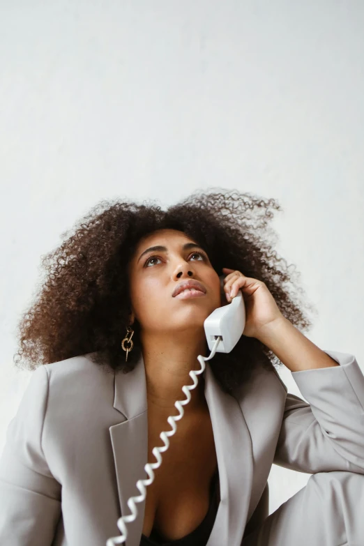 a woman sitting on the floor talking on a phone, trending on pexels, renaissance, long afro hair, serious business, pictured from the shoulders up, hovering indecision